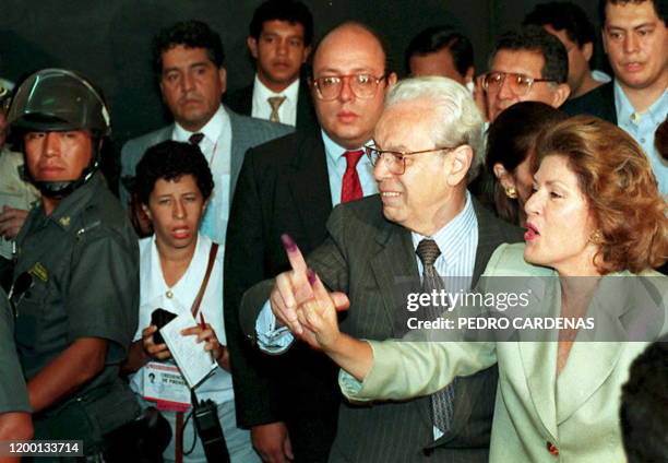 Peruvian presidential candidate Javier Perez de Cuellar and his wife Marcela Temple flash their inked fingers to reporters 09 April 1995 shortly...