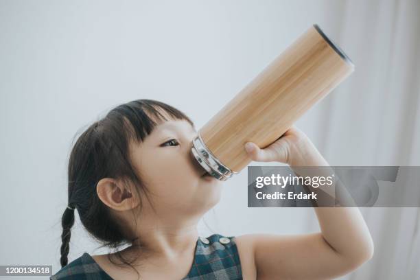 chica sedienta bebiendo agua en casa - baby cup fotografías e imágenes de stock