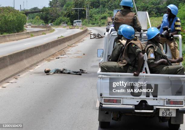 Soldiers drive past a corps during a patrol in the streets of Abidjan's polular district of Abobo on April 14, 2011. President Alassane Ouattara...