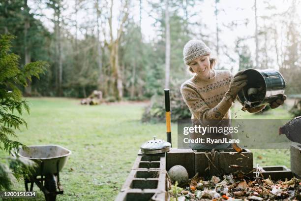 woman dumping food scrap bucket into compost pile - waste stock pictures, royalty-free photos & images