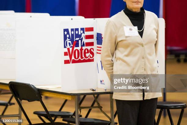 An election official stands at a booth inside a polling station at Portsmouth middle school in Portsmouth, New Hampshire, U.S., on Tuesday, Feb. 11,...