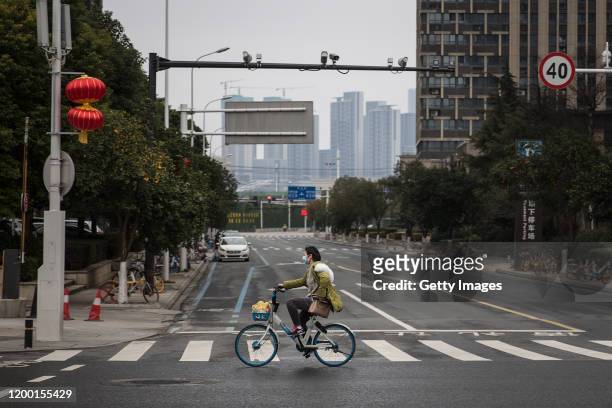 Women wears a protective mask as she rides a bicycle on February 11.2020 in Wuhan. Hubei province,China. Flights, trains and public transport...