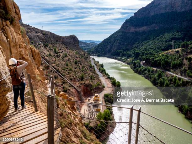 hiker in the nature walking on a wooden footbridge, nailed on the walls of rock in a gorge to great height. - caminito del rey málaga province stock pictures, royalty-free photos & images