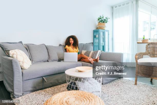 young woman on sofa with laptop - using laptop at home happy copy space stock pictures, royalty-free photos & images