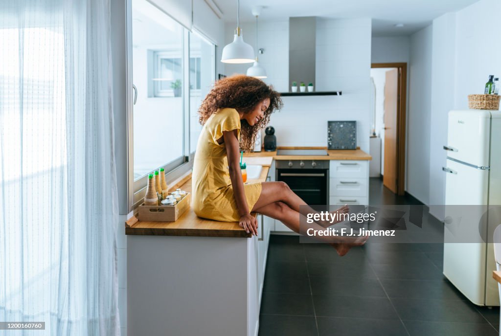 Relaxed woman sitting on the kitchen counter