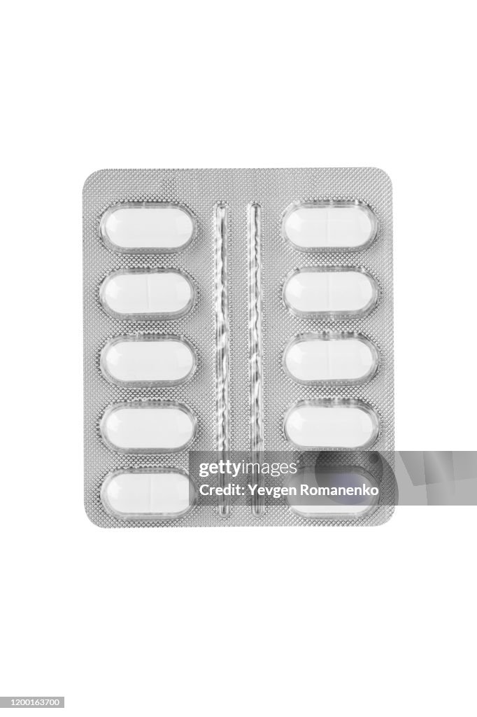 White pills in a blister pack on white background