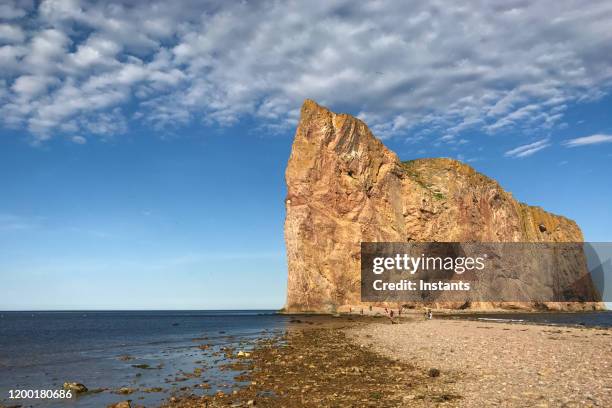 the famous rocher percé (perce rock), in percé, part of the gaspe peninsula in the canadian province of québec. incidental people are visible in background. - perce rock stock pictures, royalty-free photos & images