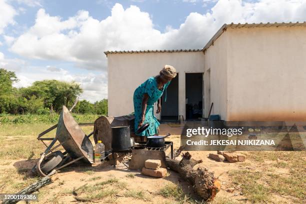 In this photograph taken on January 28 Josephine Ganye checks on a cooking pot among cooking utensils donated to her after her own were swept away...