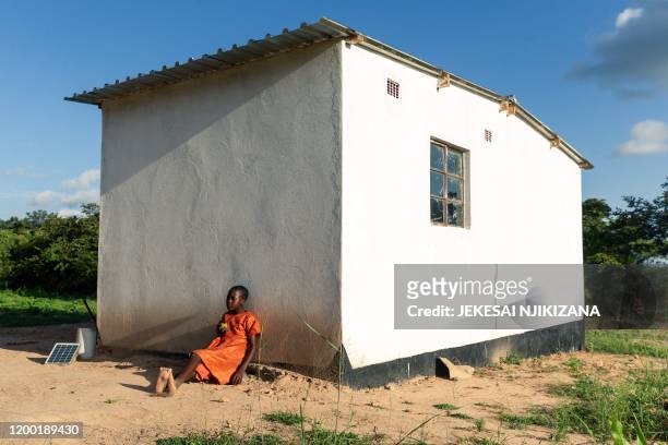 Cotilda Chiremba, the daughter of Gladys Chiremba, sits in the shade of her newly built family home as she takes a break from helping her mother weed...
