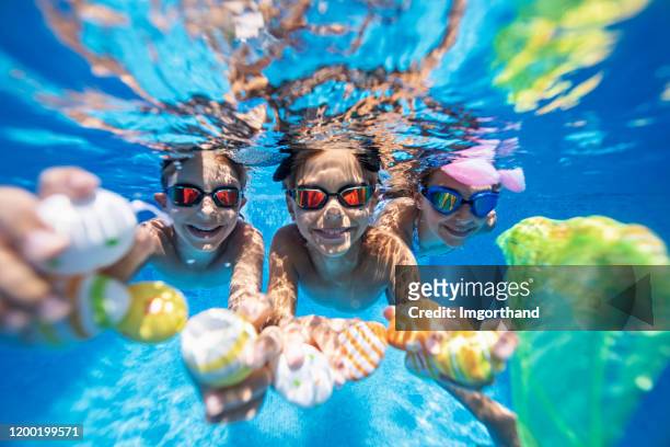 kinder spielen während der osterzeit im sommer unter wasser - children swimming stock-fotos und bilder
