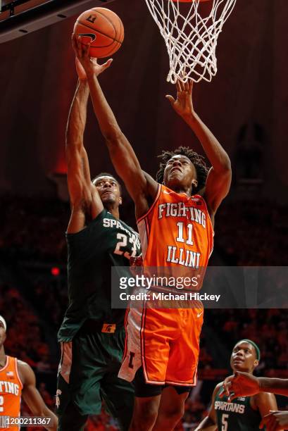 Ayo Dosunmu of the Illinois Fighting Illini shoots the ball as Xavier Tillman of the Michigan State Spartans defends from behind during the first...