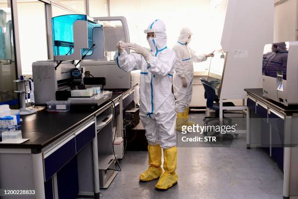 Laboratory technicians work on testing samples from people to be tested for the COVID-19 coronavirus at a laboratory in Shenyang in China's...