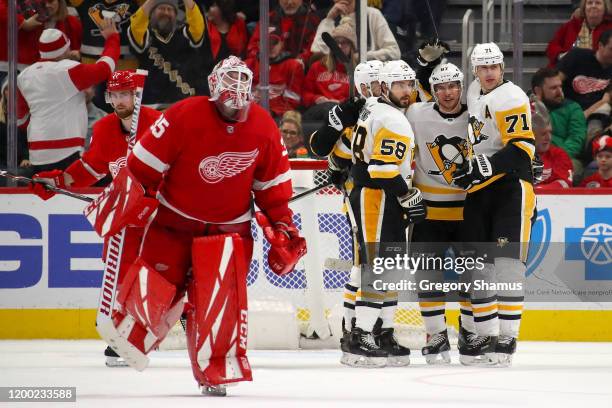 Sidney Crosby of the Pittsburgh Penguins celebrates his game winning overtime goal with Evgeni Malkin and Kris Letang behind Jimmy Howard of the...