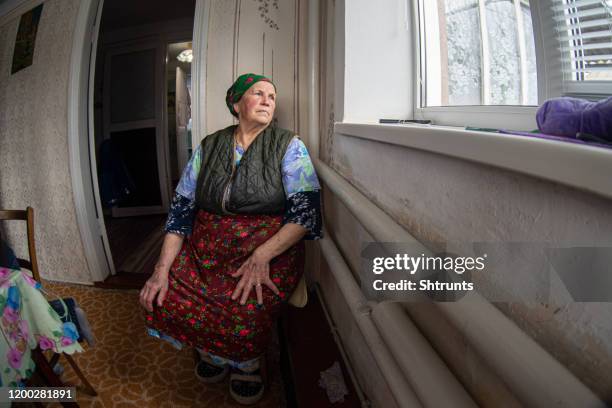 senior adult woman sitting close to a window at home - ukraina stock pictures, royalty-free photos & images