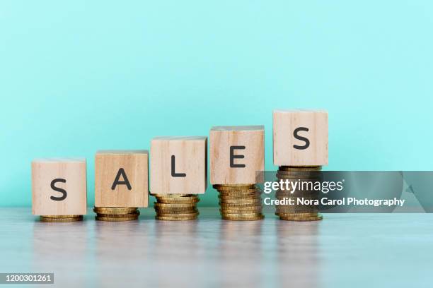 sales text on wooden block on top of coins stack - carol grow stock-fotos und bilder