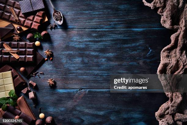 låg nyckelbild av en mängd olika choklad och bomben med torkad frukt. gammaldags stil på ett blått rustikt bord med kopierings utrymme - bombones chocolate bildbanksfoton och bilder