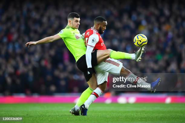 Alexandre Lacazette of Arsenal tackles with John Egan of Sheffield United during the Premier League match between Arsenal FC and Sheffield United at...