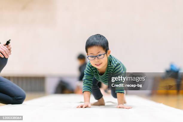 kind met down syndroom beoefenen gymnastiek met instructeur - gymnastic asian stockfoto's en -beelden