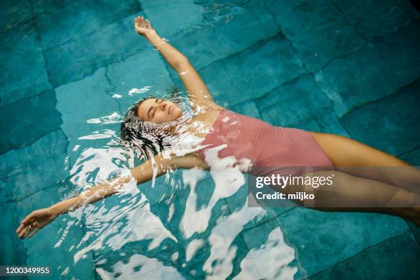 hermosa joven mujer relajándose en el interior junto a la piscina - woman pool relax fotografías e imágenes de stock