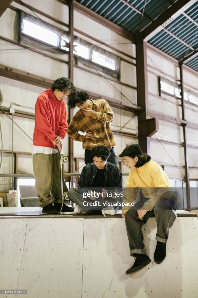 Group of skateboarders watching video from a smartphone.