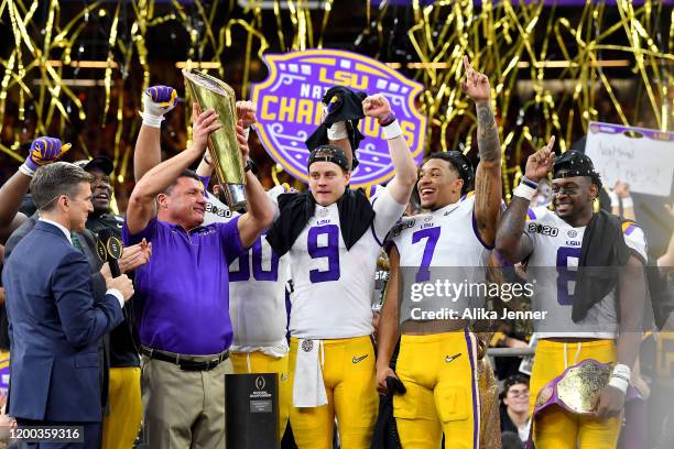 Head coach Ed Orgeron of the LSU Tigers raises the National Championship Trophy with Joe Burrow, Grant Delpit, and Patrick Queen after the College...