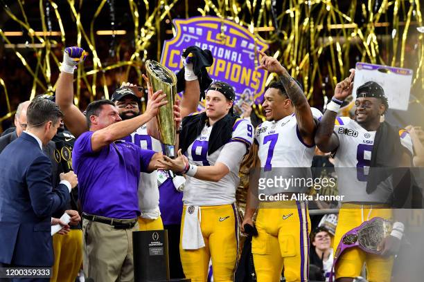 Head coach Ed Orgeron of the LSU Tigers raises the National Championship Trophy with Joe Burrow, Grant Delpit, and Patrick Queen after the College...