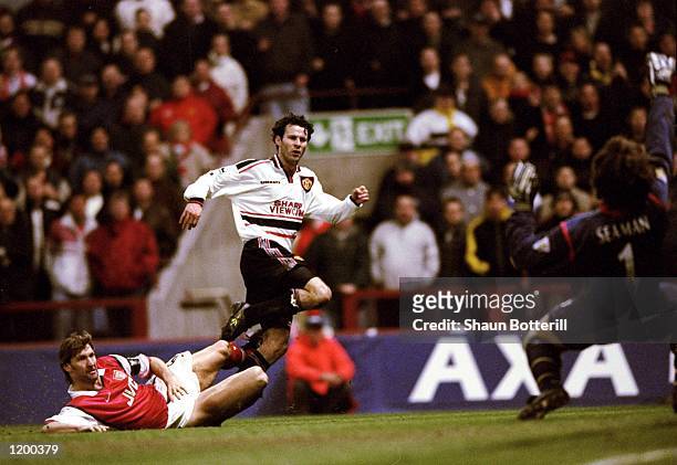 Ryan Giggs of Manchester United beats the despairing lunge of Tony Adams of Arsenal to drive the ball past David Seaman to score the winner in the FA...