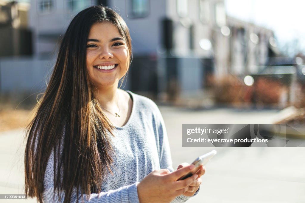 Attraktive Generation Z Junge Frau der hispanischen Ethnizität mit einem Smartphone