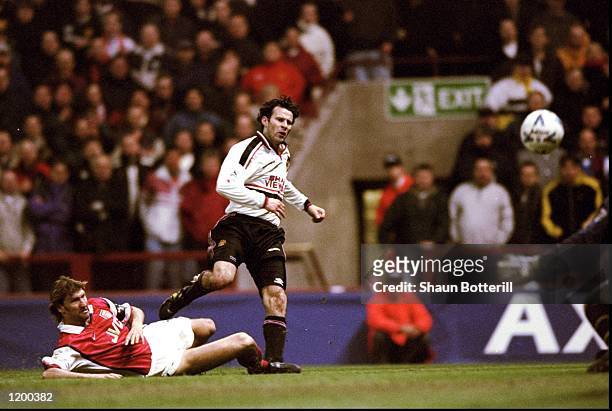 Ryan Giggs of Manchester United beats the despairing lunge of Tony Adams of Arsenal to drive the ball past David Seaman to score the winner in the FA...