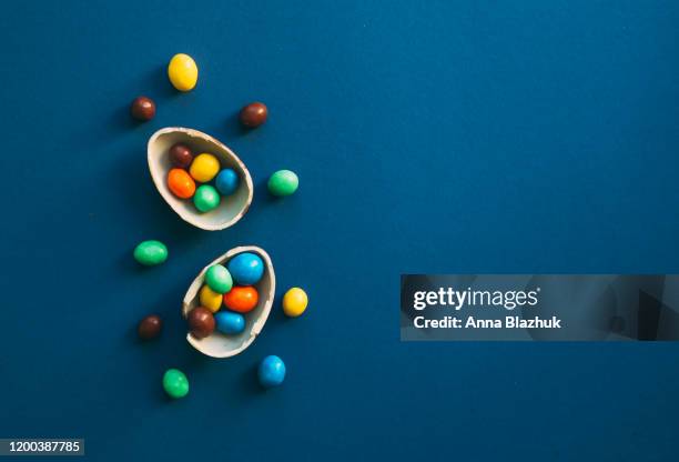 chocolate easter eggs with colorful candies over classic dark blue background - food photography dark background blue imagens e fotografias de stock