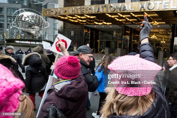 Marchers wearing pink hats hold up a middle finger as they walk in front of Trump International Tower during the Woman's March in the borough of...