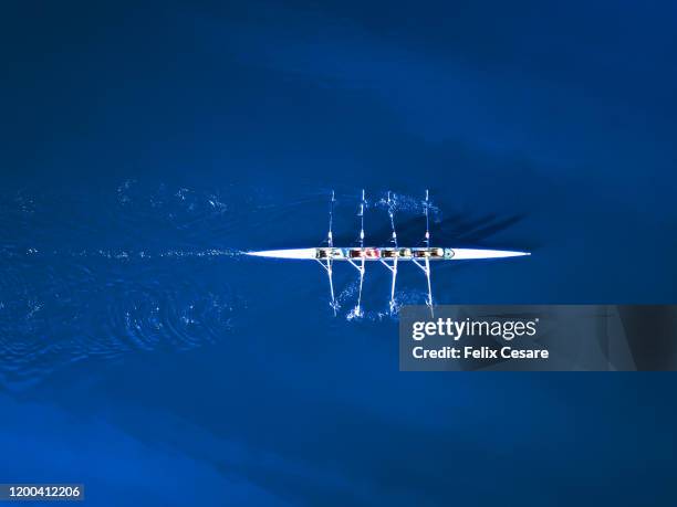 aerial view of a rowing boat surrounded by classic blue water - sport and team photos et images de collection