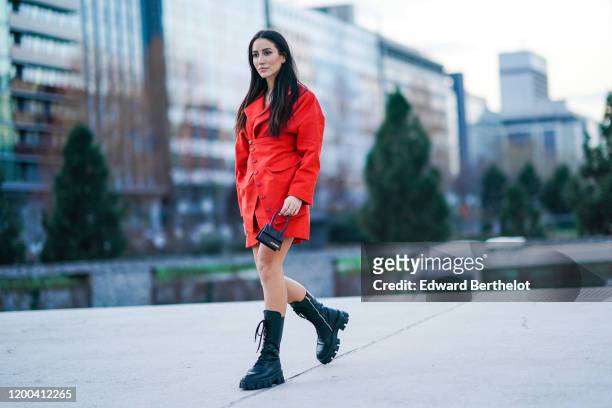 Tamara Kalinic wears a red dress/coat, a Jacquemus mini bag, black boots, outside Jacquemus, during Paris Fashion Week - Menswear F/W Fall/Winter...