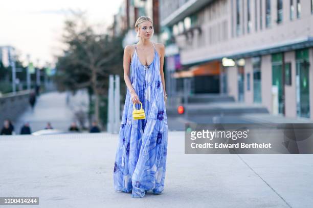 Leonie Hanne wears a blue floral print low neck ruffled dress, a yellow Jacquemus mini bag, outside Jacquemus, during Paris Fashion Week - Menswear...