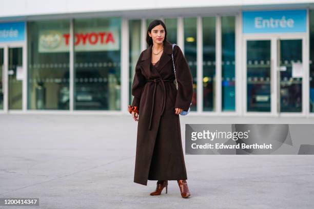 Bettina Looney wears a brown long coat, a blue Chanel bag, brown leather high heeled shoes, outside Jacquemus, during Paris Fashion Week - Menswear...