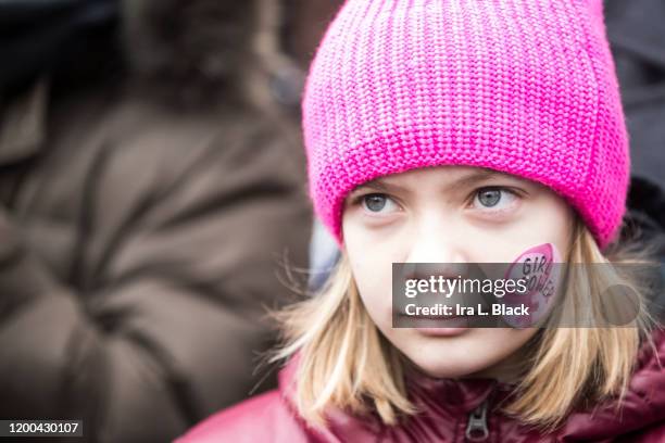 Young marcher wearing a pink hat and a sticker that says "Girl Power" with the female symbol on it during the Woman's March in the borough of...