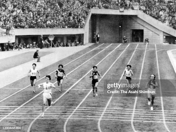 Dorothy Hyman of Great Britain crosses the finish tape to win the Women's 200m during the Tokyo International Sports Championships at the National...