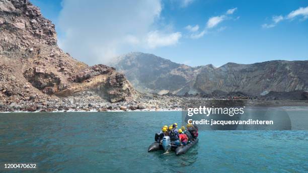 a group of tourists sails with an inflatable boat towards the white island volcano in new zealand, looking towards the crater - white island new zealand stock pictures, royalty-free photos & images