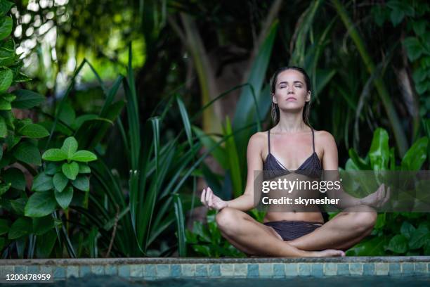 young woman meditating by the pool in summer day. - lotus position stock pictures, royalty-free photos & images