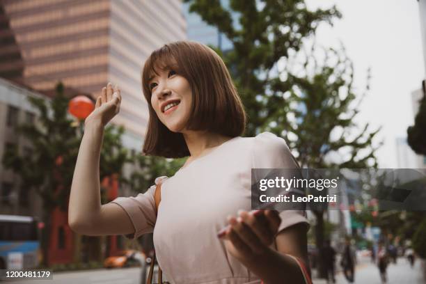 woman hailing a ride in seoul downtown - welcome korean stock pictures, royalty-free photos & images