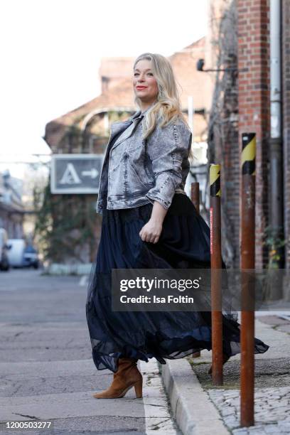 German presenter, curvy model and plus size influencer wearing a dark blue dress with ruffles and a jeans jacket by Marina Rinaldi and brown suede...