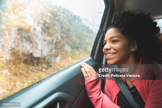 teen mädchen auf roadtrip genießen berglandschaft - winter car window stock-fotos und bilder