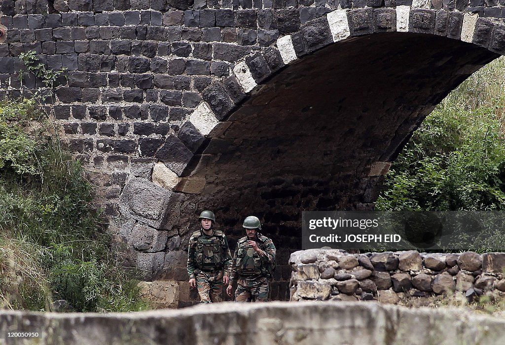 Syrian soldiers patrol the river bed whi