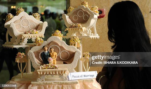 Sri Lankan woman passes a butter sculpture of a traditional Buddhist wedding at a culinary competition in Colombo on July 29, 2011. Dozens of local...