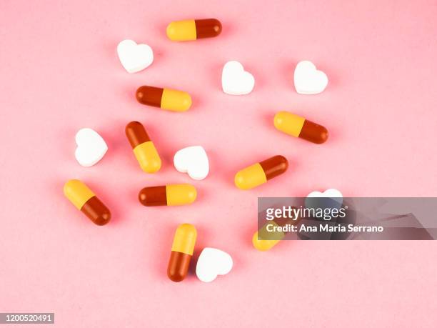 heart-shaped pills and colored pills - heart pill stockfoto's en -beelden