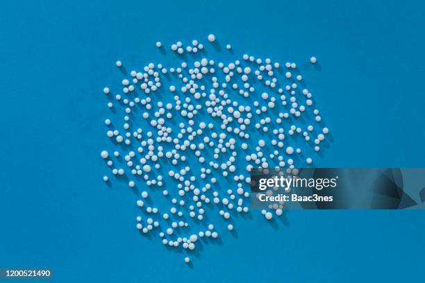 small polystyrene balls on blue background - granulat kunststoff stock-fotos und bilder