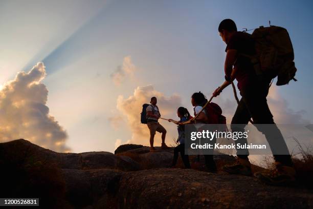 group of friends hikers climbing up silhouette mountain cliff - people climbing walking mountain group stockfoto's en -beelden