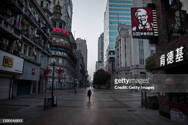 Resident wears a protective mask as she walk on an empty business street on February 13, 2020 in Wuhan, Hubei province, China. Flights, trains and...