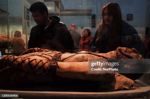 Visitors look at an ancient Egyptian mummy in the British Museum in London, England, on February 13, 2020. The museum, one of London's top tourist...