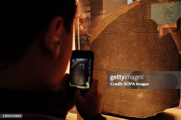 Visitor takes photos of the Rosetta Stone in the ancient Egypt section of the British Museum in London. The museum, one of London's top tourist...